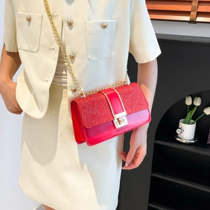 Chic red glitter square crossbody bag with gold chain strap worn on a woman's shoulder