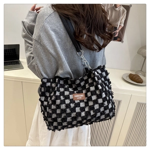 Detail of checkered tote bag with plush texture and leather logo on home background