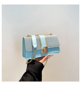Detail of light blue crossbody bag with knit stitching and golden chain strap