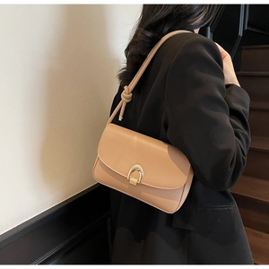 Detail of beige leather baguette bag with horseshoe buckle and knot shoulder strap