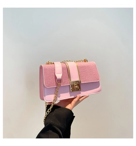 Close-up of pink leather crossbody bag showing woven texture and gold metal chain strap