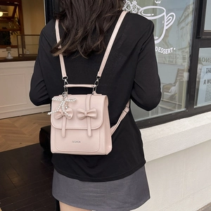 Pink PU mini backpack with butterfly bows and pearl pendant shown in a lifestyle setting