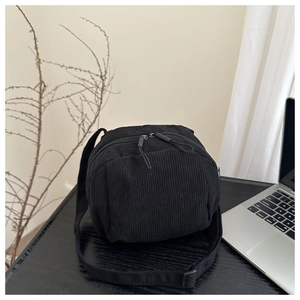 Gros plan détaillé du sac bandoulière noir en velours côtelé avec double fermeture