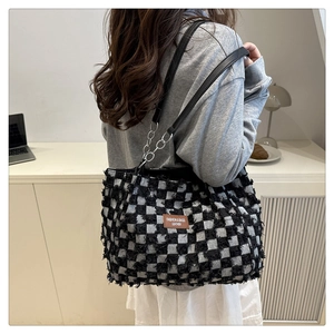 Detail of checkered tote bag with fringe texture and metallic chain on the shoulder strap