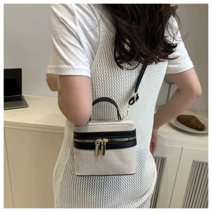 Detail of the woven fabric and black leather box bag with gold metal hardware