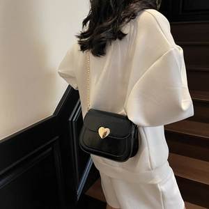 Fashionable black semi-circle crossbody bag with gold heart clasp and chain strap