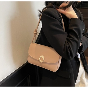 Minimalist apricot shoulder bag with horseshoe buckle and knot detail shown on model