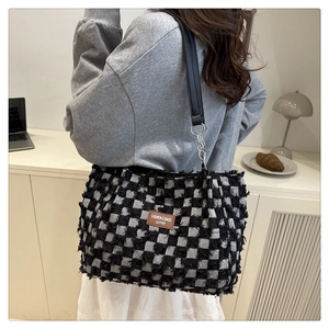 Detail of checkered tote bag showing rich tweed texture and premium leather logo patch