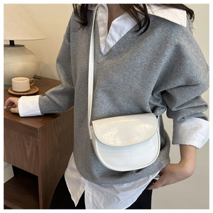 Detailed view of a white PU leather saddle bag with adjustable strap in a lifestyle setting