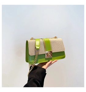 Detail of the woven texture and green leather flap with a gold metal lock on the bag