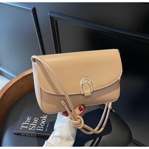 Detail of beige shoulder bag with golden horseshoe lock and unique knotted strap design