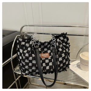 Close-up of black and white checkered tote bag featuring fringed edges and chain strap