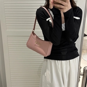 Pink hobo shoulder bag with gold metal bow shown in a mirror selfie style for sizing