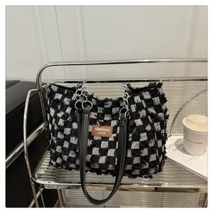 Detail of checkered tweed tote bag with frayed edges and leather brand tag