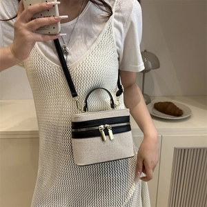 Canvas and PU leather box bag with black trim and gold zippers on a white dress model