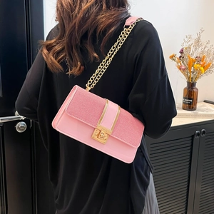 Pink minimalist crossbody bag with woven texture and gold chain strap on a model