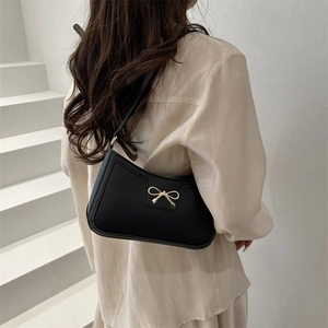 Minimalist black faux leather underarm bag with a decorative gold bow for women