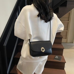 Chic black leather crossbody bag with golden U-shaped buckle on a stylish model