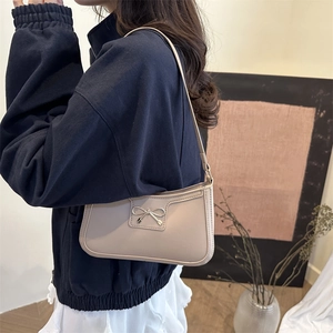 Elegant beige underarm baguette bag with metallic bow detail for women's daily commute