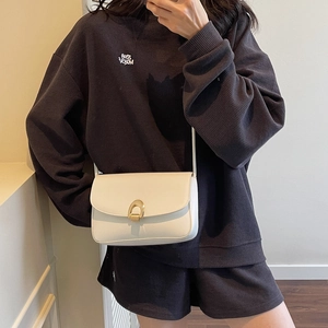 Chic white leather crossbody bag with golden horseshoe buckle and minimal flap design