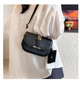 Detalle de bolso de silla negro minimalista con cierre dorado y monedero pequeño extra