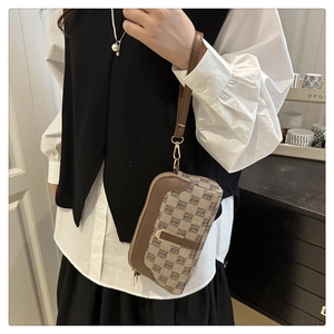 Detailed shot of a vintage jacquard clutch bag with brown leather trim and wrist strap