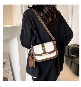 Detalle del bolso de silla retro con ribete marrón, hebilla dorada y mini monedero colgante