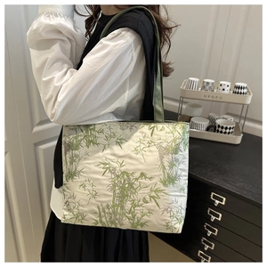 Lifestyle shot of a woman wearing a large tote bag with a green bamboo print pattern