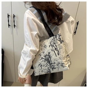 Detailed side view of white canvas tote bag with black ink bamboo print on shoulder