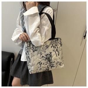 Détail d'un grand cabas en toile avec motifs de bambou noir porté par un mannequin