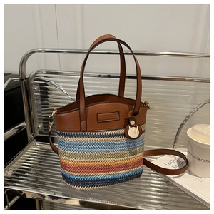Détail du sac seau en paille tressée colorée avec finitions en cuir brun et pendentif