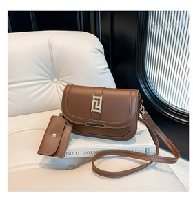 Detalle de bolso de montura marrón oscuro con cierre dorado sobre asiento de cuero blanco