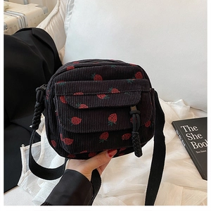 Detailed view of black corduroy mini crossbody bag with cute red strawberry patterns