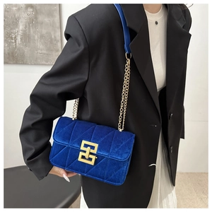 Detail of blue velvet crossbody bag with quilted stitching and gold chain strap