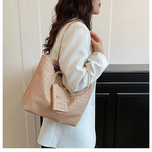Fashionable beige tote bag with houndstooth texture and hanging purse shown on shoulder