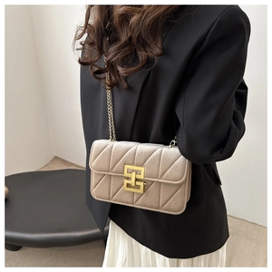 Detail of champagne velvet quilted crossbody bag with golden chain and geometric clasp