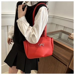 Close-up of the red tote bag with a silver metallic bow and smooth faux leather texture