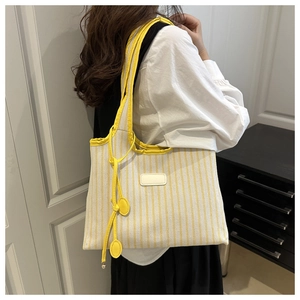 Detail of a large capacity striped tote bag with yellow and white vertical patterns