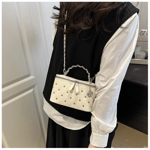 Detail of cream quilted crossbody bag featuring silver studs and rose pendant