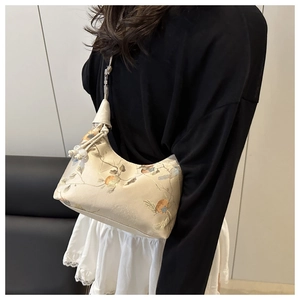 Close-up of beige satin handbag with flower embroidery and pearl drawstring details