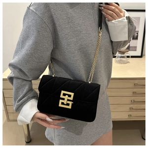 Detail of black velvet crossbody bag with golden geometric lock and chain strap