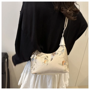 Close-up of bird and floral embroidery with pearl drawstring on cream dumpling bag