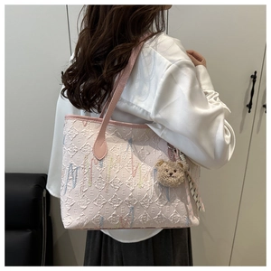 Macro shot of pink jacquard tote bag with E-pattern and plush bear charm accessory