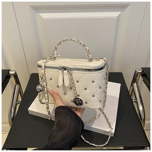Detail of white quilted crossbody bag with silver studs and black camellia charm
