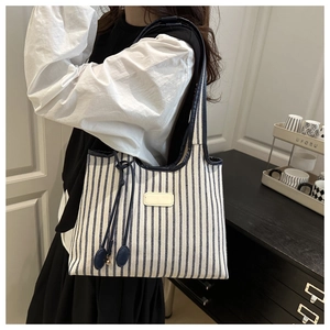 Detail of navy blue and white striped tote bag with leather tag and decorative drawstring