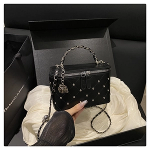 Detail of black leather crossbody bag with silver studs and rose charm in a gift box