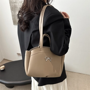 Minimalist khaki tote bag with silver bow accent and shoulder straps on a model