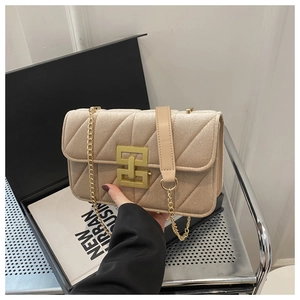 Detail of velvet quilted shoulder bag featuring gold chain strap and geometric metal buckle