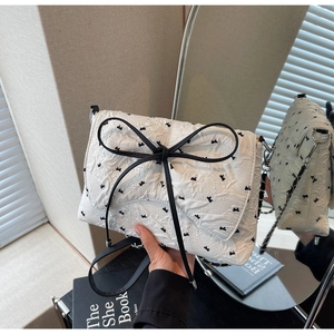 Detail of white seersucker shoulder bag with black butterfly patterns and bow accent