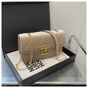 Close-up of beige velvet quilted bag with golden geometric lock inside a gift box